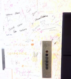 Express Yo'self Wall at Brandeis: jumble of illegible words near a series of buttons on the wall.