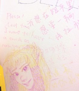 Express Yo'self Wall at Brandeis: realistic drawing of girl's face and hair. Chinese writing. Please! Next time I want to have a crush on a non-gay...[illegible, obscured by drawing of girl]