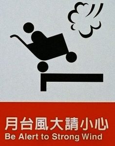 Sign in Taipei subway station, "be alert to strong wind" with image of baby in stroller blown off a platform