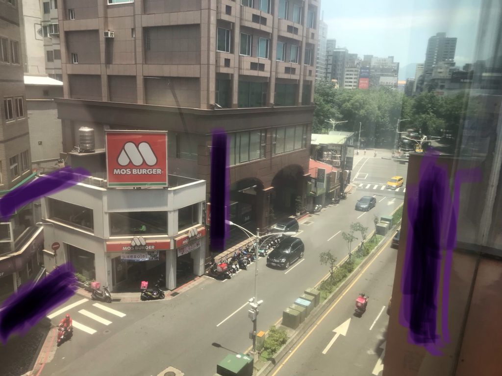 urban street scene from a 4th-floor window somewhere in China, with a few cars and scooters, and a restaurant called MOS BURGER