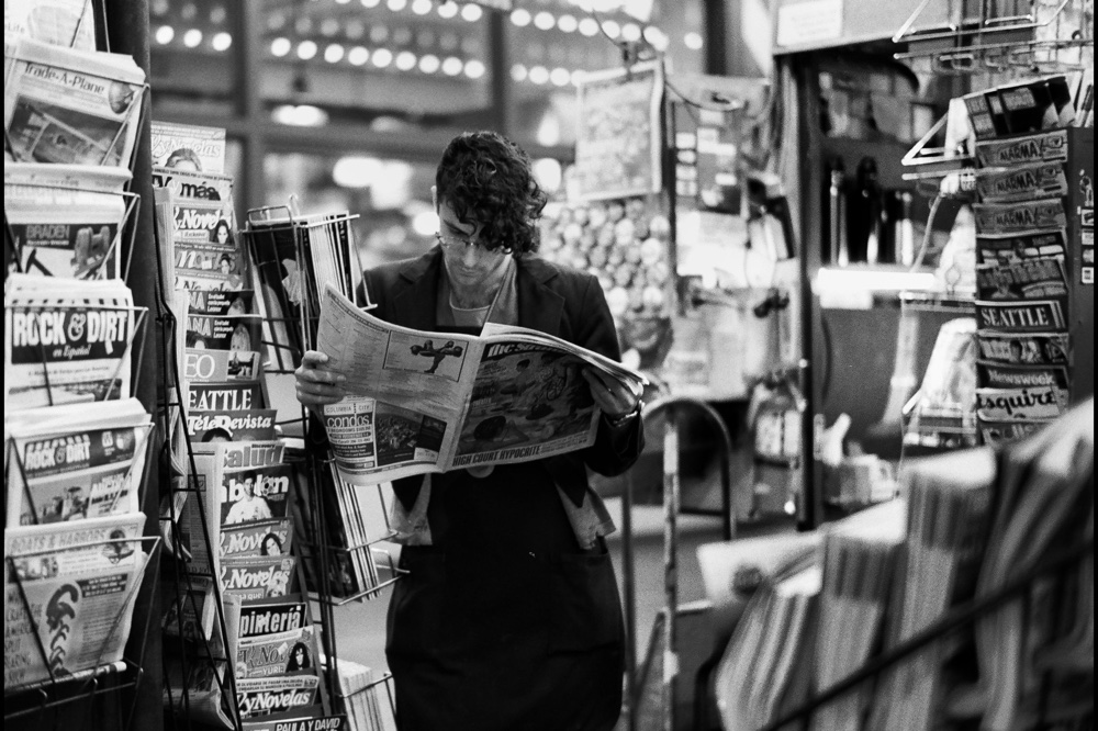man reading a newspaper in a news stand