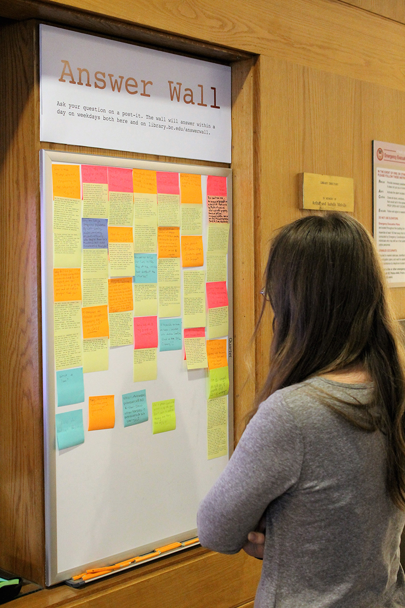 A student looks at the Answer Wall, covering in Post-its
