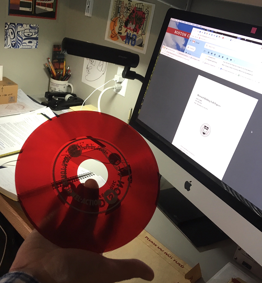 An Edison Voicewriter dictation machine disc held by Jack Kearney. It is red, flexible, and translucent.