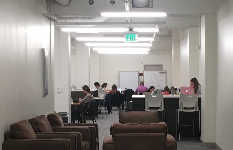 A view into the new study space with cushioned chairs in the foreground and students at worktables in the background.