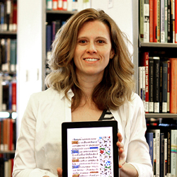 Photo of Melanie Hubbard holding an iPad with a background of books