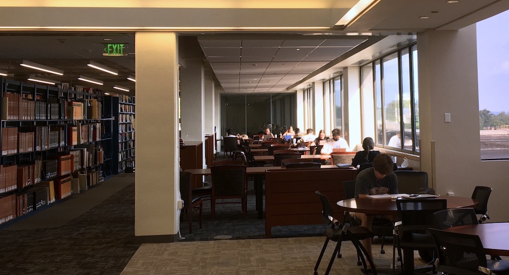 Several students seated at tables study intently in bright morning sun flooding through windows