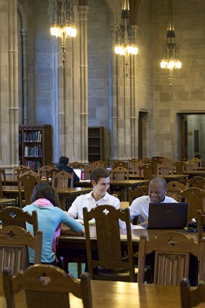 Three students chat. They are smiling and look as if they are having a nice time.