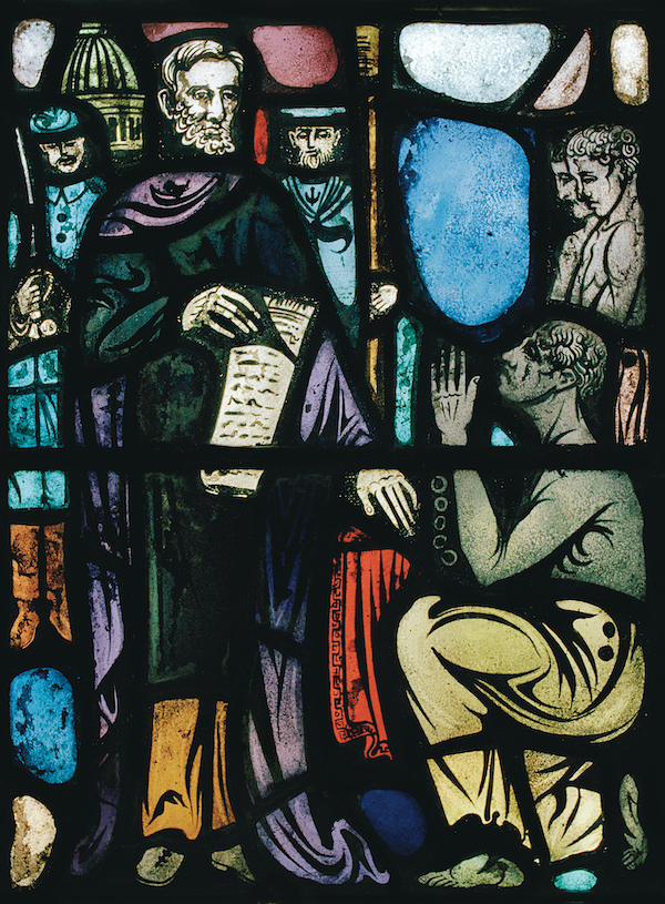 Stained glass window representing Lincoln holding a paper, standing, in black and purple robes, and a black man in ragged slacks, shirtless, kneeling on one knee.