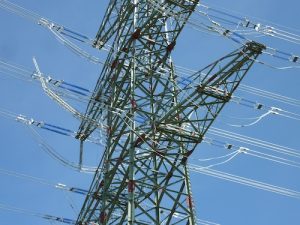 A high-powered electric line tower viewed from below against a blue sky